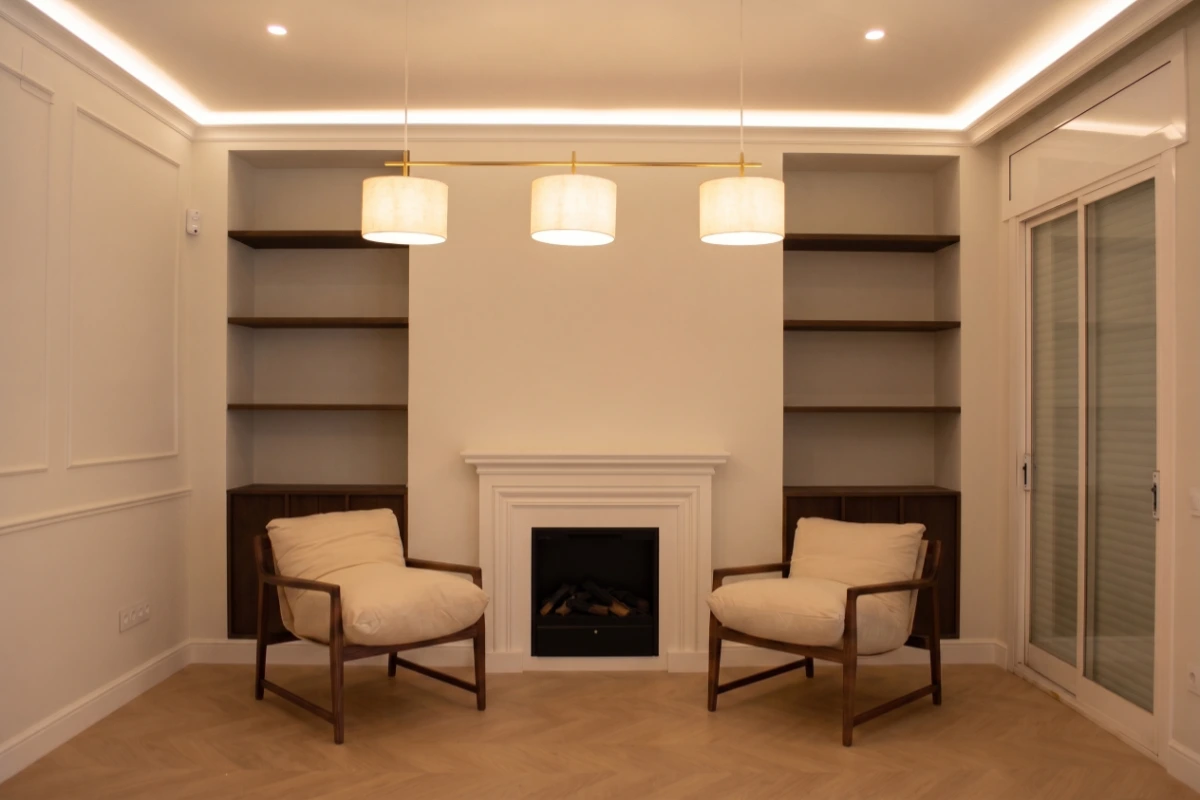 reforma integral en la calle Balmes Barcelona salón estilo clásico con chimenea y sillones. Iluminación led. Proyecto de interiorismo. Cornisas con luces LED